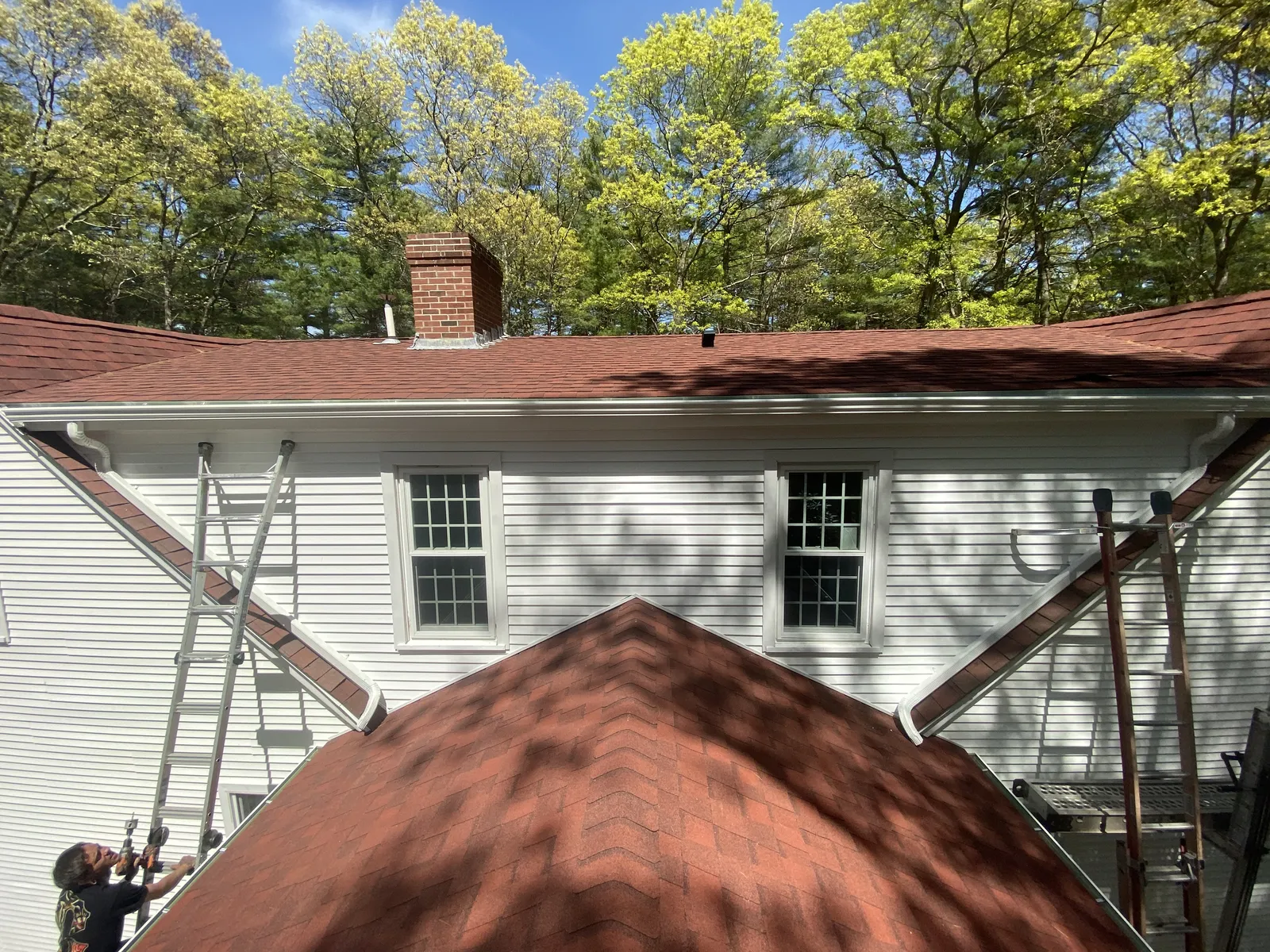 Rear roofline with newly installed white seamless gutters on a red shingle roof