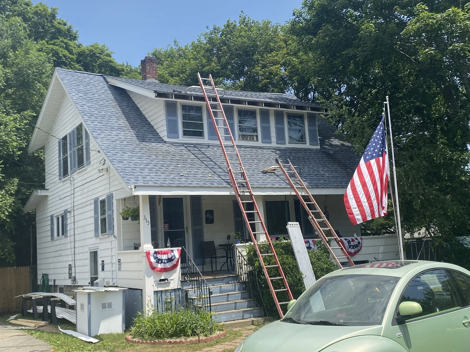 White two-story home with ladders in place during seamless gutter installation