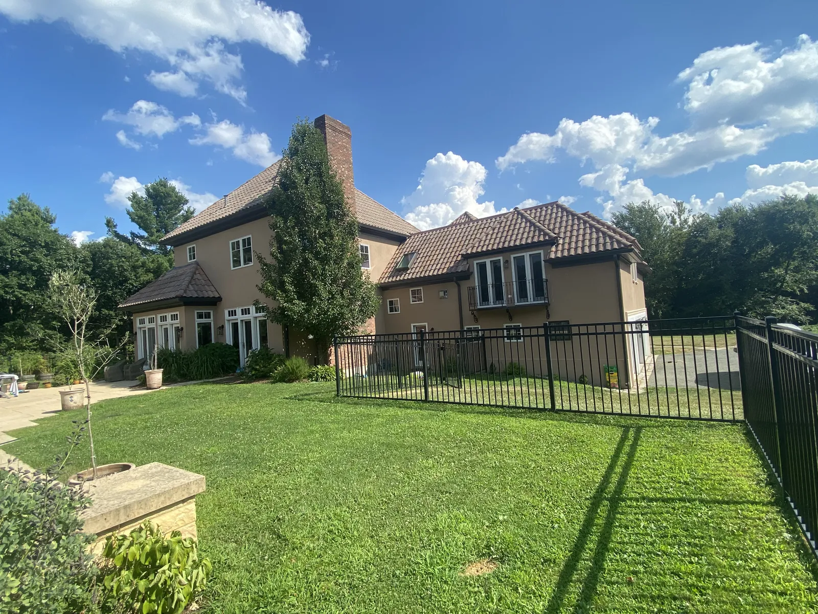 Rear lawn view of a stucco home with a dark seamless gutter system