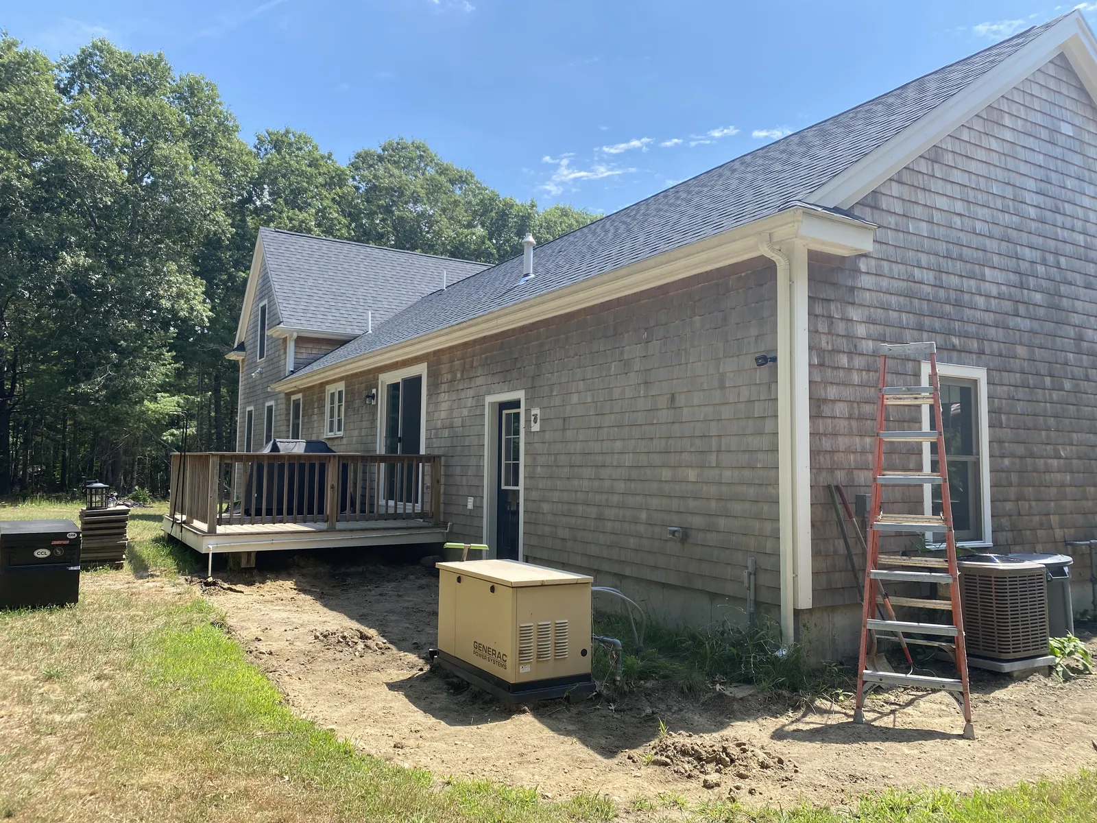 Rear side of a cedar shingle home with new white seamless gutters